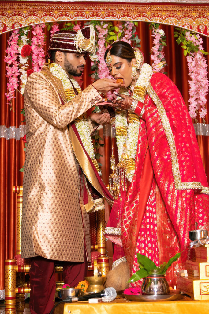 Indian wedding photography. Groom feeds Bride.