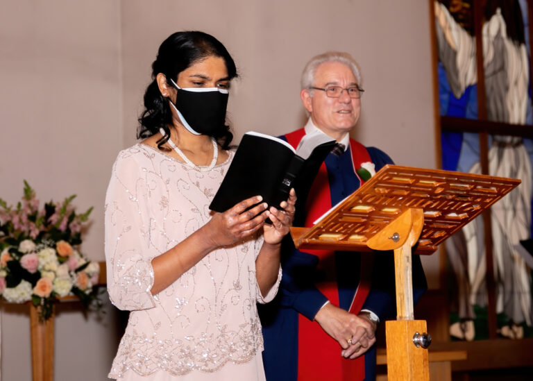 Indian Sister reads a passage from the Bible. Minister listens to the Reading.