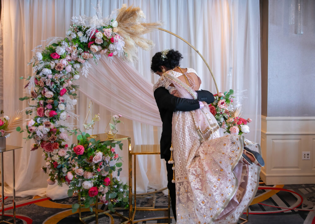 Indian Groom lifts and swings his new Bride in his arms.