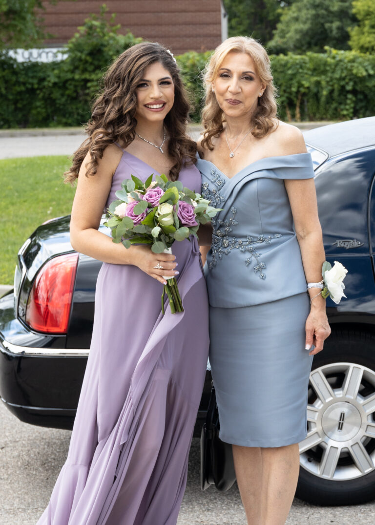 Mother of Bride and Sister with flowers outside limo image.