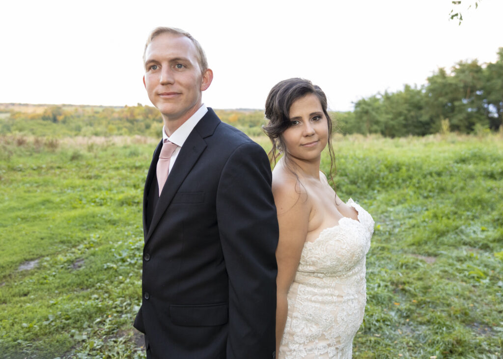 Bride and Groom back to back posed image in an open field.