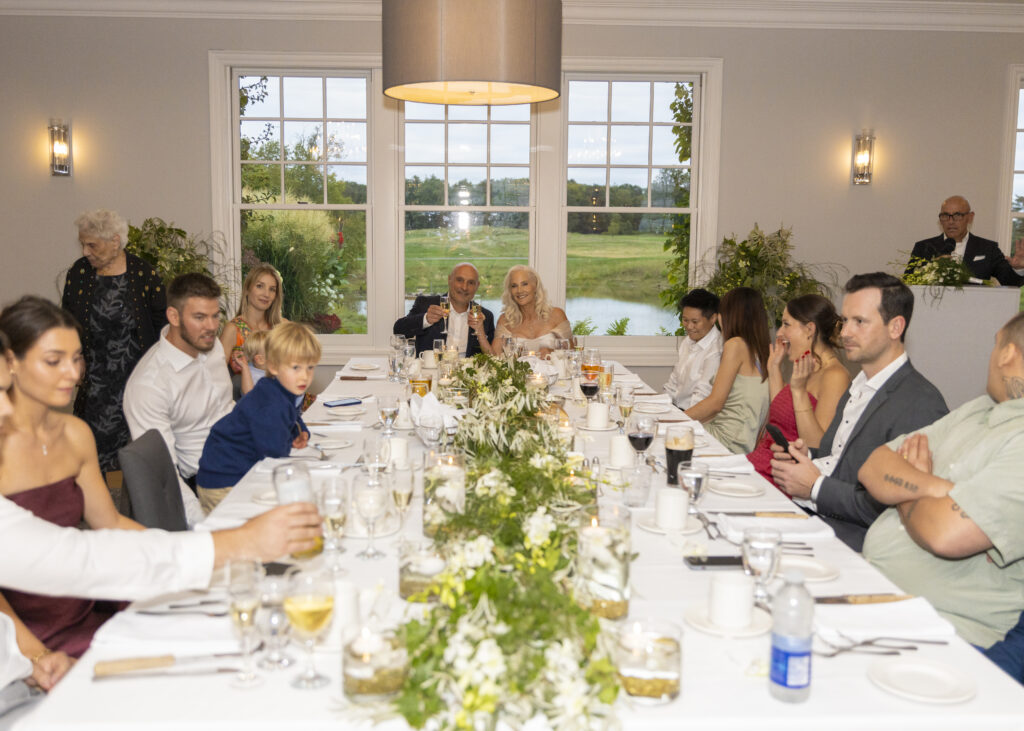Wide angle Wedding Photography image of a Bride and Groom toasting their Guests at Dinner.
